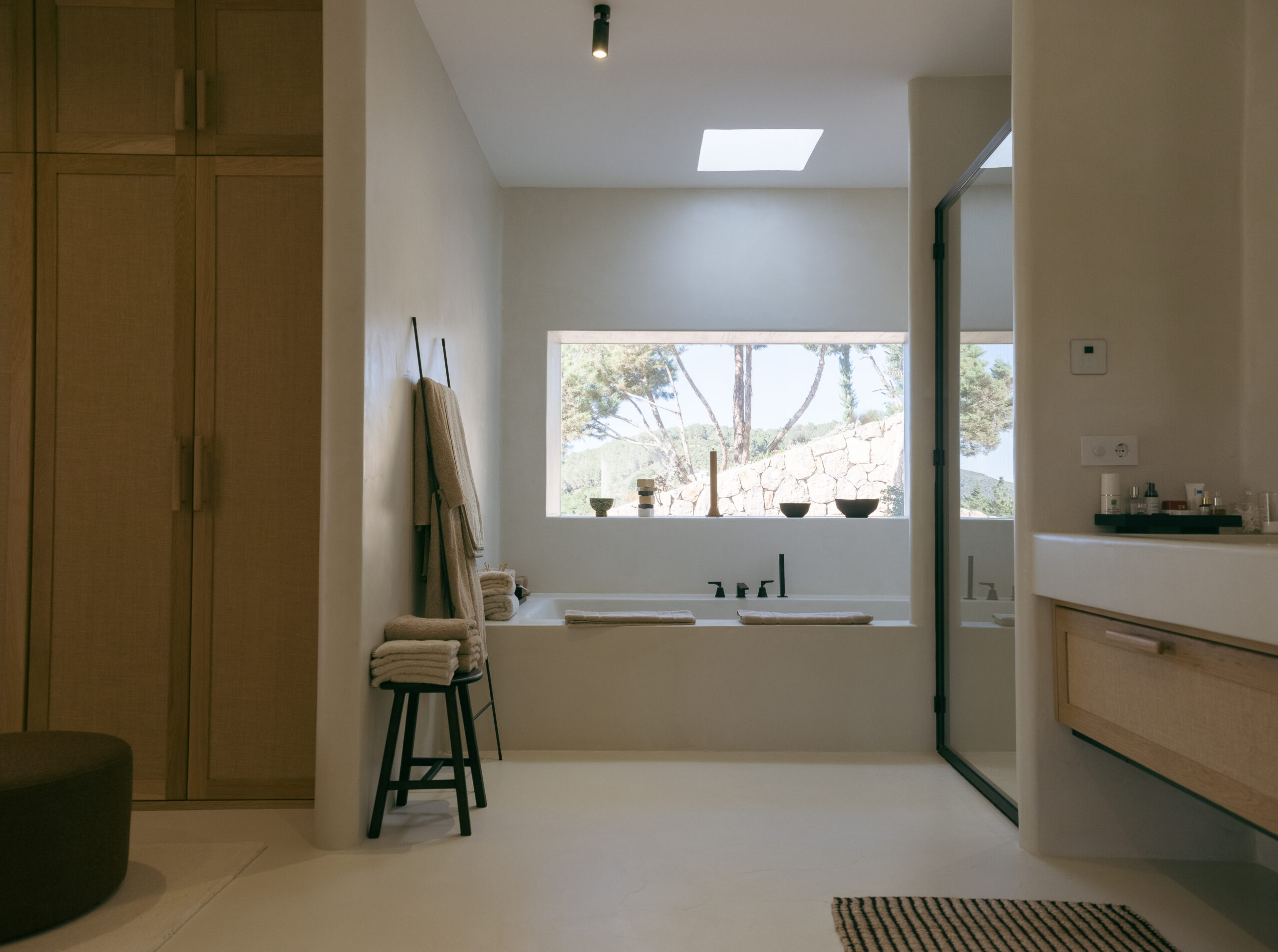 Muebles de baño a medida en madera junto a bañera y ventana panorámica