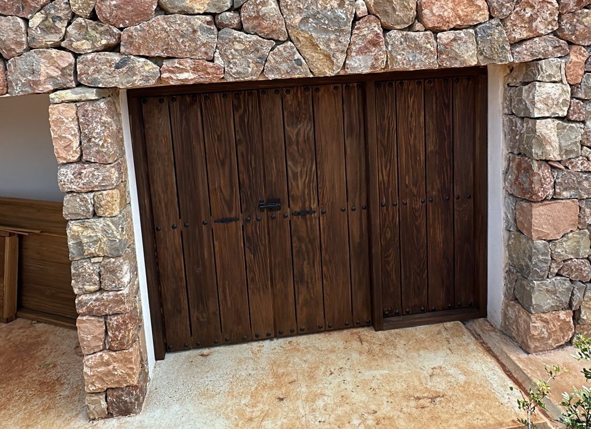 puerta_1 Rustic wooden doors with black iron fittings set in a stone wall